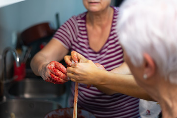 Mujeres sujetan una tripa de ternera durante la elaboración de morcillas artesanales de arroz de Burgos. Tomada el 20 de febrero de 2020 en Burgos, Castilla y León.