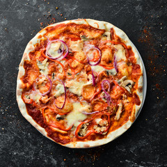 Homemade pizza on a black stone background. Italian cuisine. Top view. Free space for your text.