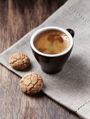 Cup of coffee with amaretti (Italian biscuits) on rustic wooden background. 