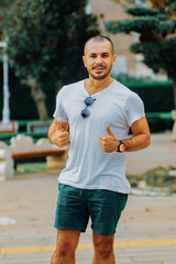 Handsome young male model in a park. young man posing outside. male model with sunglasses and summer clothes.