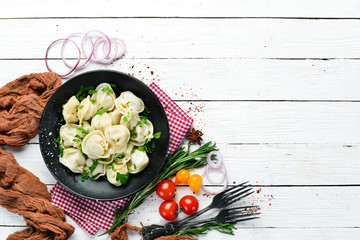 Russian pelmeni meat Dumplings with greens in a black plate. Russian traditional cuisine. Top view. Free copy space.