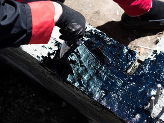 Woman hand with a brush covers the strip foundation with bituminous mastic for waterproofing