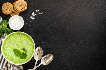 Broccoli vegan cream soup in bowl on black table from above copy space