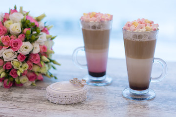 Wedding bouquet of roses on a table with wedding rings and coffee