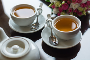 Wedding rings in teaspoons with tea on a mirror table