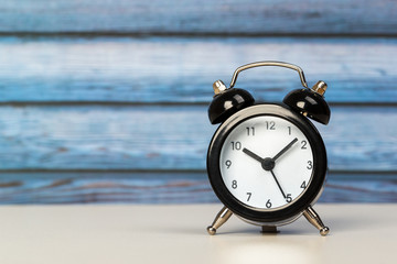 Black retro alarm clock with bells on a wooden table, daily routine concept.