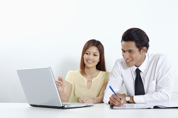 Cheerful businessman and businesswoman working on laptop together