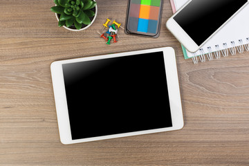 White digital tablet and mobile phone on an office working dark wooden table.