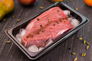 fresh meat with spices in ice on dark background 