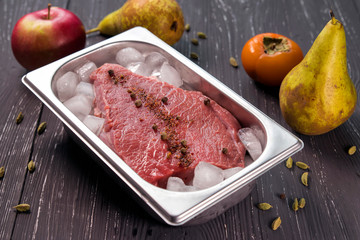 fresh meat with spices in ice on dark background 