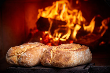 whole wheat bread in a wood oven, two freshly baked bread in a bakery with a traditional oven, the...