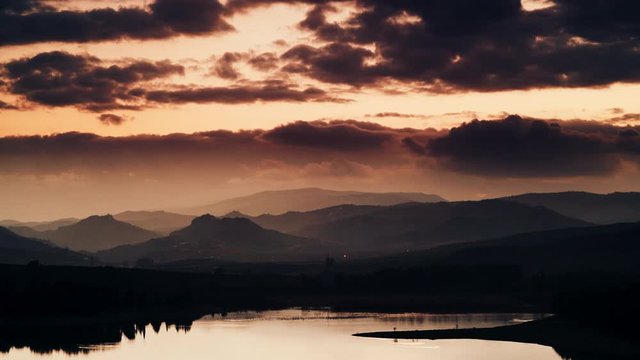 Time lapse of dark clouds at sunset moving over spanish hilly landscape and lake Embalse del Guadalhorce, Ardales Reservoir, Malaga Andalusia, Spain."