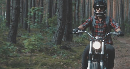 Fototapeta na wymiar Young rider driving motorcycle on forest road