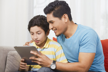 Obraz premium Father and son using a digital tablet together