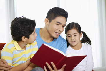 Father reading a book with his children
