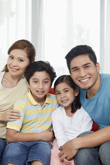 Family of four cheerfully smiling at the camera