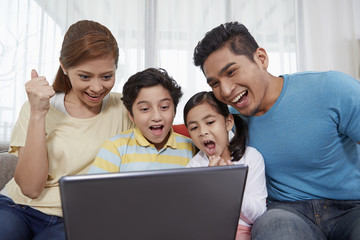 Family of four sitting and using laptop together