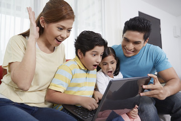 Family of four sitting and using laptop together