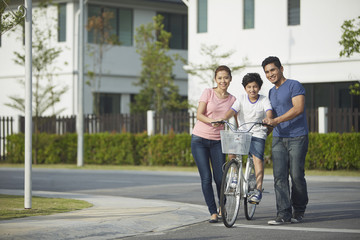Fototapeta premium Parents teaching son how to ride a bicycle