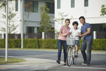 Parents teaching son how to ride a bicycle