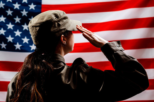 Veterans Day, Memorial Day, Independence Day. Silhouette of a female soldier saluting against the background of the American flag. The concept of the American national holidays and patriotism