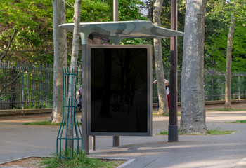 Bus stop billboard Mockup in empty street in Paris. Parisian hoarding advertisement close to a park...
