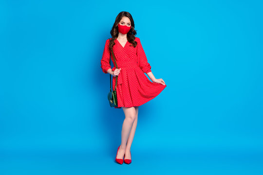 Full size photo of pretty lady keep social distance people walk outside breathe air alone wear dotted red short dress stilettos clutch protect face mask isolated blue color background