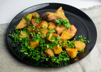 a piece of chicken lies on a potato with greens on a black plate