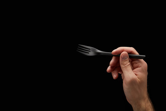 Hand With Black Fork On Black Background 