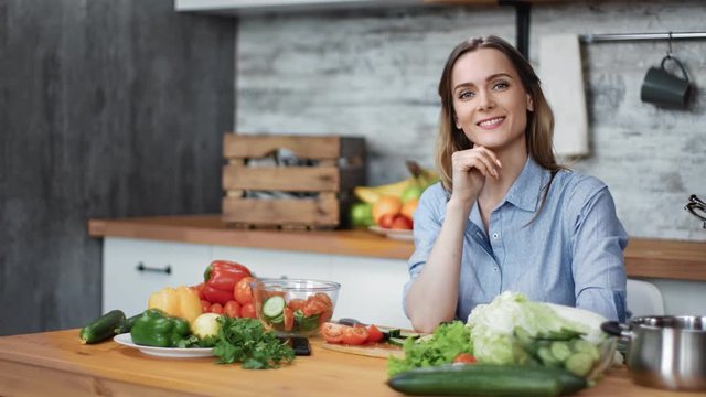 Portrait of housewife posing sitting at table with fresh vegetables. Medium shot on RED camera