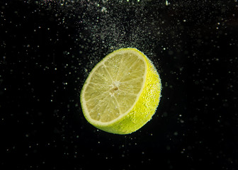 air bubbles on lime thrown into water on a black background. Lime detailing and focus