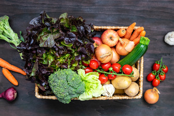 Frisches rohes regionales Gemüse in einer Kiste auf einem braunen Holz Tisch. Draufsicht, Biokiste, Versand, gesunde Ernährung. - obrazy, fototapety, plakaty