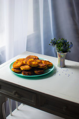 curd pancakes lie on a blue plate.
little blue flowers in a vase on a white table.
curd pancakes and flowers on a white background