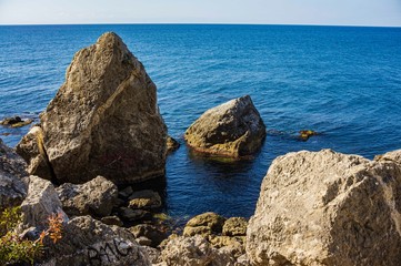 Rocky coast of Black Sea. Cape Alchak. Wildlife near ancient city built by Genoese. Velvet season in Sudak in Crimea. Huge stones and boulders in sea and on background of sea. Close-up.