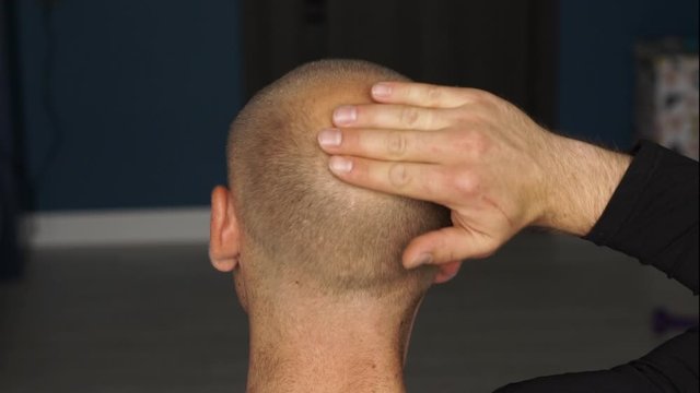 Blond man about 30 years old is touching his bald head and caressing with his palm