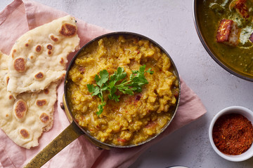 Indian red lentil curry soup dal with rice naan. Vegan indian dish on concrete background
