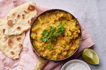 Indian red lentil curry soup dal with rice naan. Vegan indian dish on concrete background