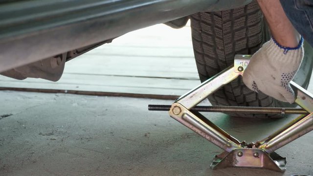 lifting the car with a jack screw to replace the wheel
