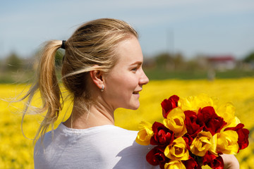 Fototapeta premium The young woman with tulips in the tulip field