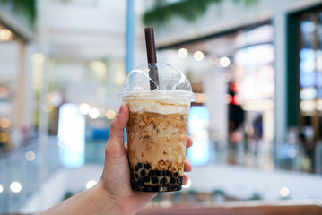 Iced Boba/Bubble Milk tea. A plastic cup of milk tea with boba/bubble tapioca pearls and brown...