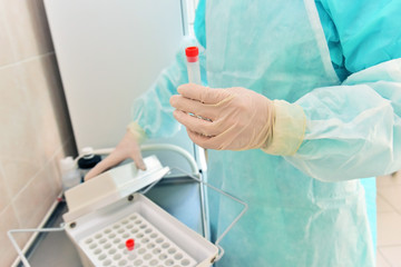 A nurse in a protective suit, holding a test tube in her hand, makes a test for the virus.