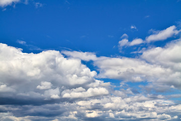 Cloudscape. Blue sky and grey clouds. Sunny day. Cumulus clouds.