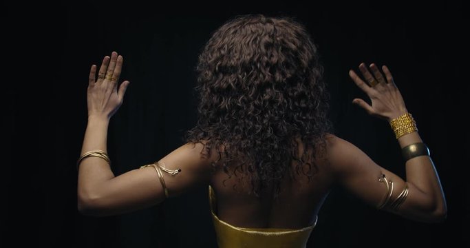 Belly dancer in gold dress is wearing jewelry, dancing on black background, 4k