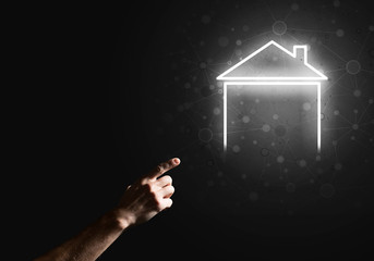 Conceptual image with hand pointing at house or main page icon on dark background