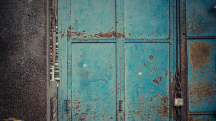 blue rusted door with rusty chains with padlock