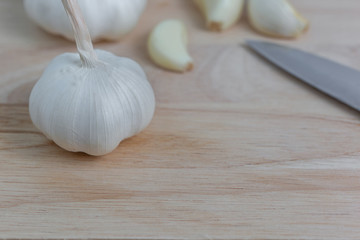 Raw white garlic, garlic on a wooden chopping board with peeled garlic pieces.