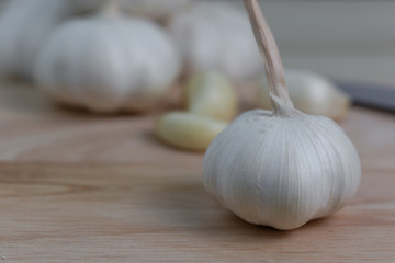 Top view with close-up white garlic on a wooden floor and peeled garlic slices blurred the background.garlic