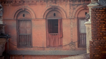 brick red wall with wooden window and railing