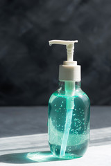 For antiseptic treatment of hands in a period of coronavirus. A bottle of gel on a gray background. Hand disinfection and treatment with the product. Clear blue antiseptic gel.