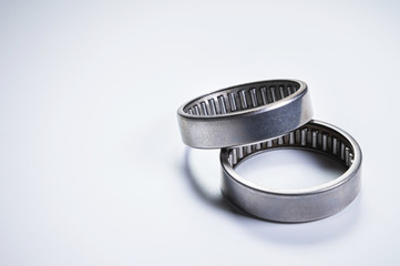 A pair of needle-bearing roller bearings on a gray background. The concept of new car parts